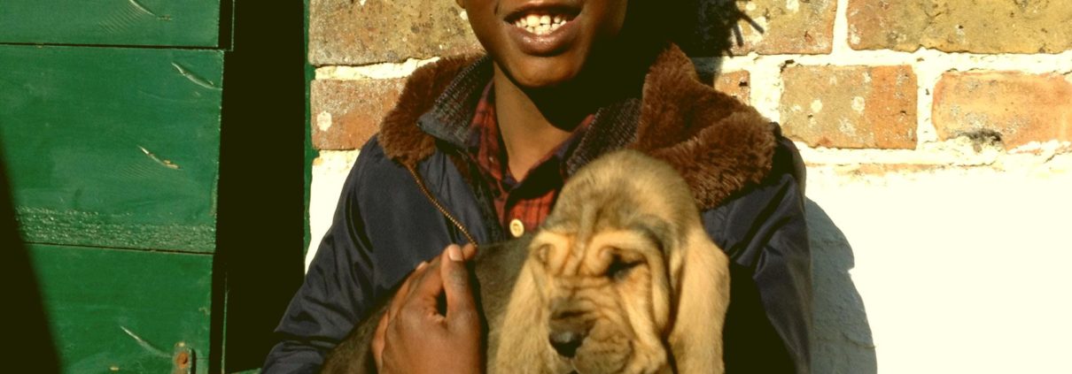 Emile houdt een pup in zijn armen naast een groene poort